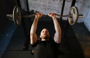 a man lifting an EZ bar with weight plates on both sides while lying on a gym bench