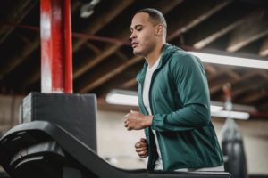 a man wearing a green top and running on a treadmill at the gym